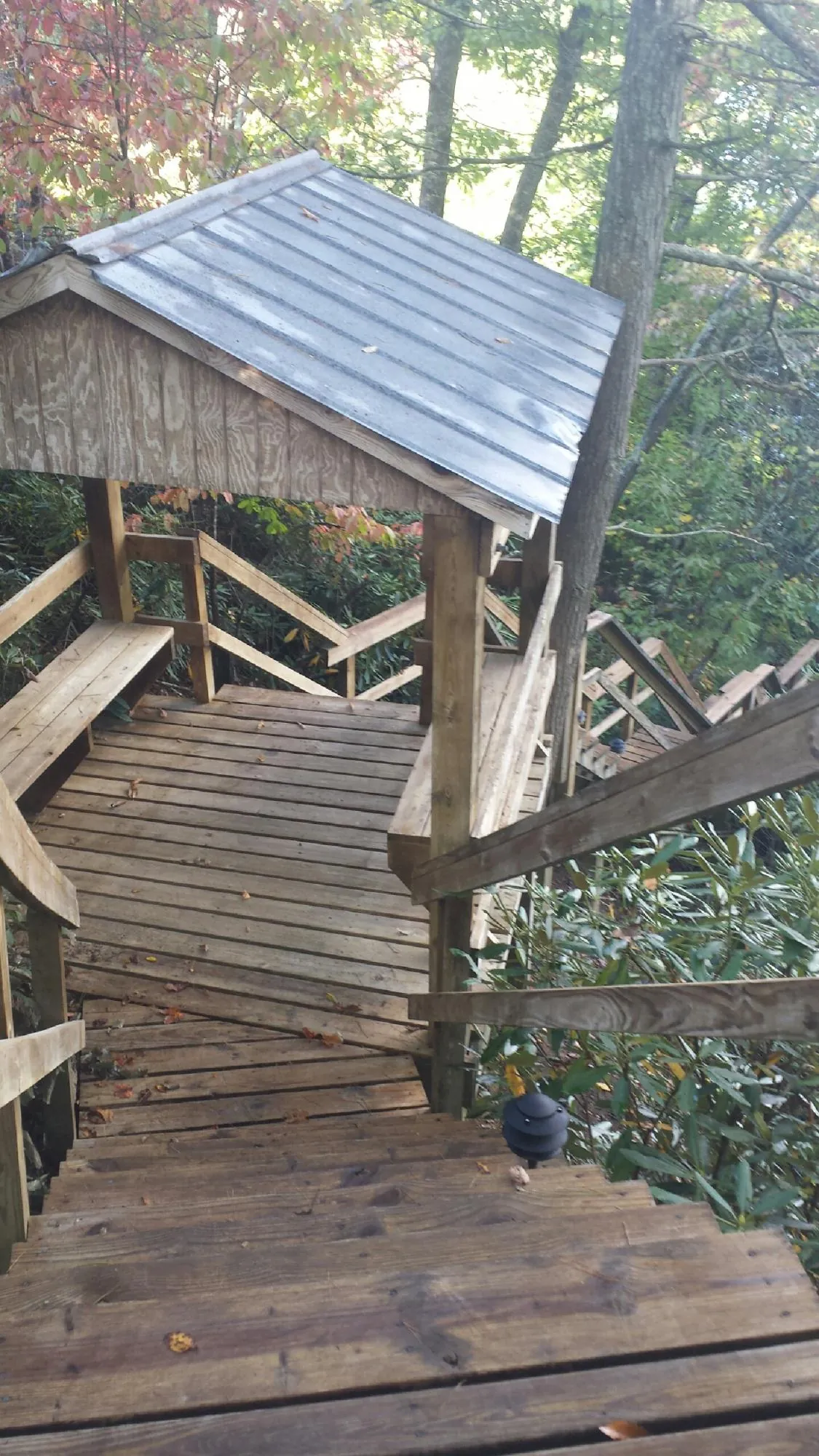 Metal roofed shelter over wooden steps on a wooded walkway — Skylight Repair & Installation work by our crew in Colchester