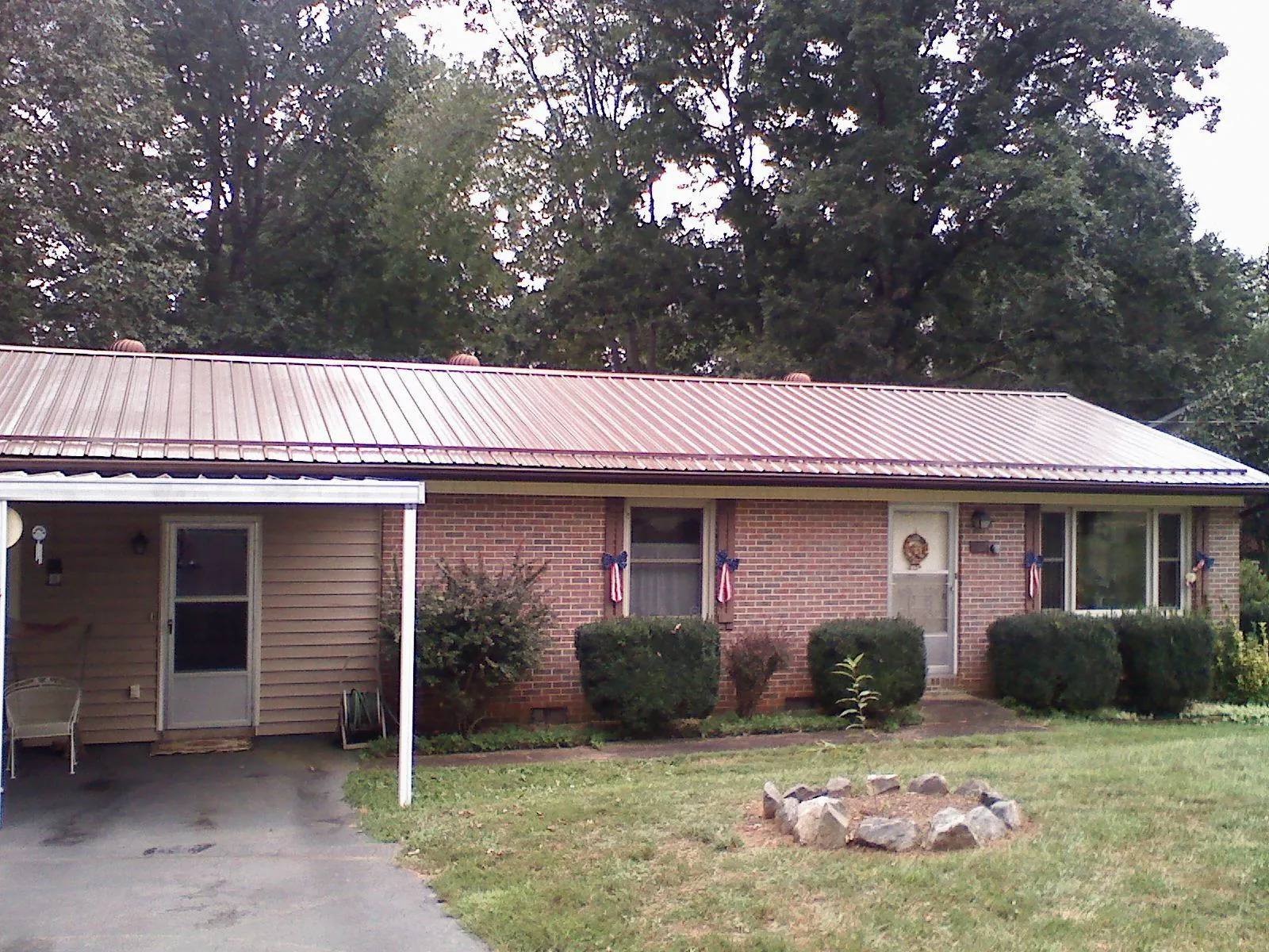 Bronze metal roof and carport on a brick ranch home — Roof Repair work by our crew in Colchester